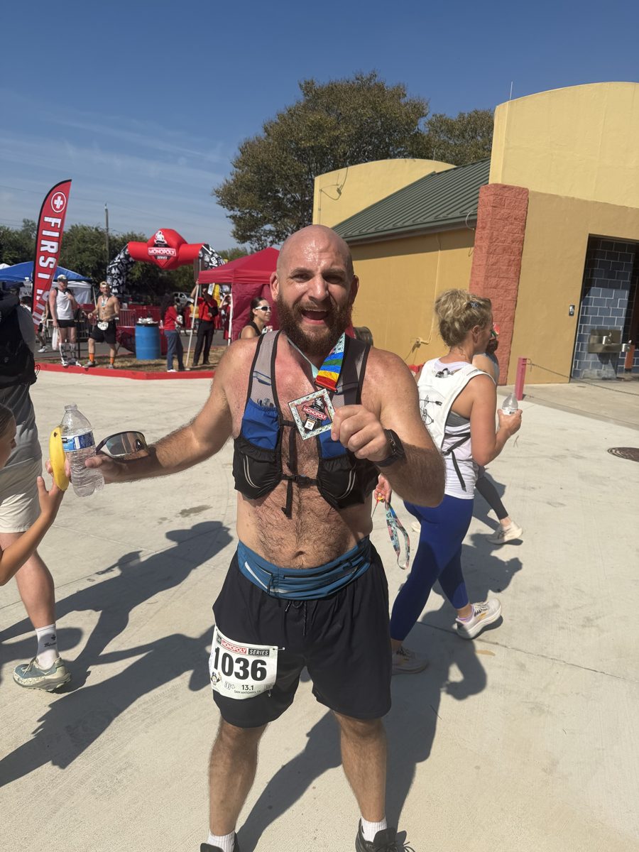 Smiling at the finish line, holding up the finisher medal